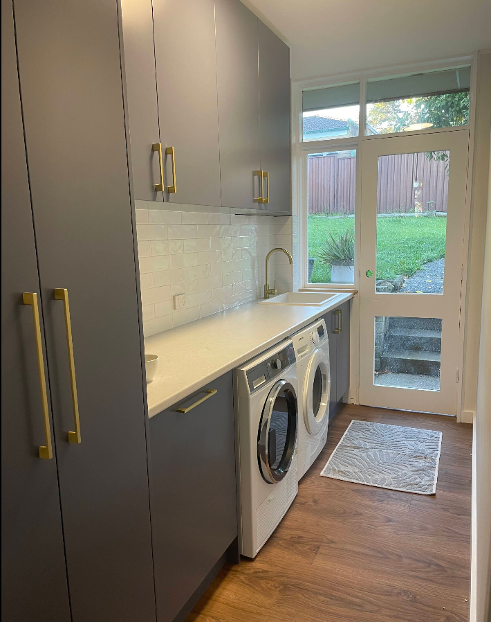 Grey laundry cabinetry with brass handles